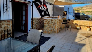 An outdoor patio with a stone wall, a glass table, and a flag.