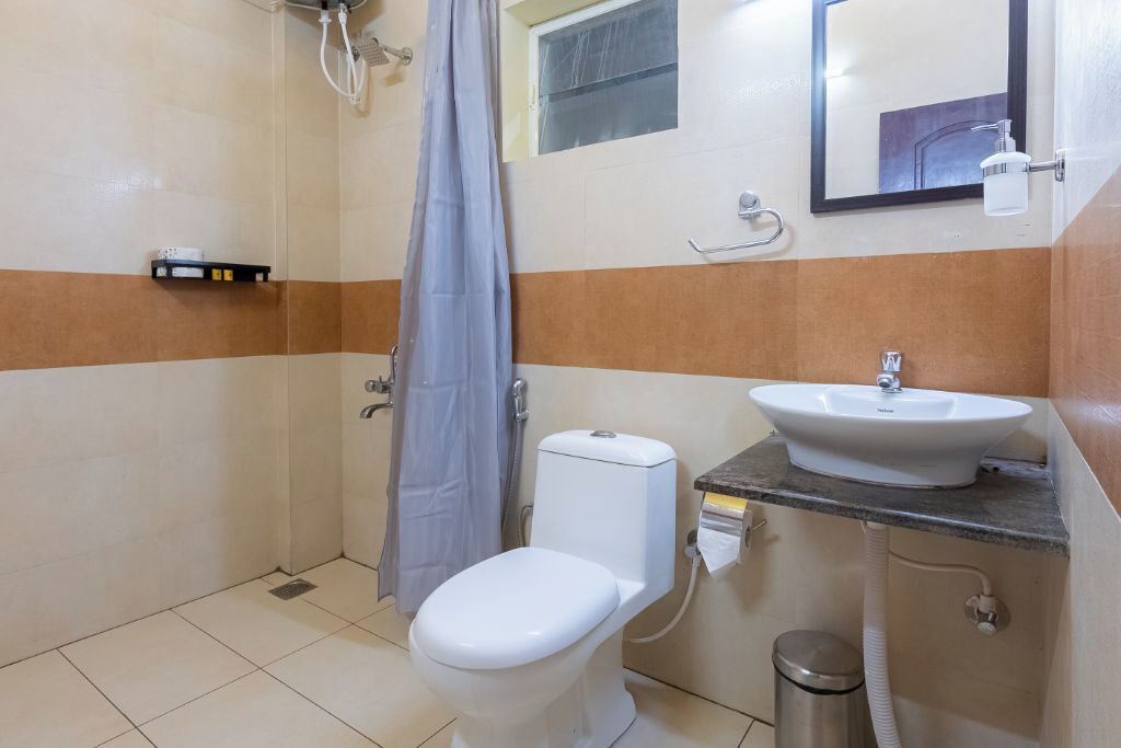 A small bathroom with a toilet, sink, and shower.
