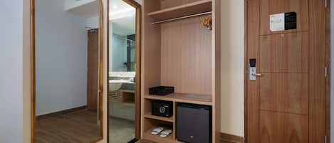 Una habitación con un armario de madera, un espejo y un electrodoméstico pequeño, posiblemente un mini refrigerador o un calentador.