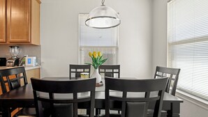 A dining area with a round table, black chairs, a vase with yellow flowers, and a hanging light fixture. - Relax, Quiet, Clean, & 15min Away From Airport (Houston)