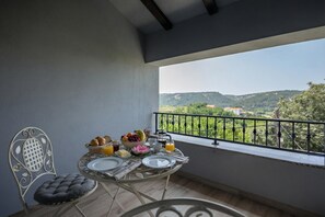 A balcony with a table set for breakfast, a chair, and a view of green hills. - Harmony House Vito, Lopar, Croatia (Lopar)