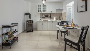 Una cocina moderna con armarios blancos, un comedor con mesa y sillas, y un carrito pequeño con objetos.