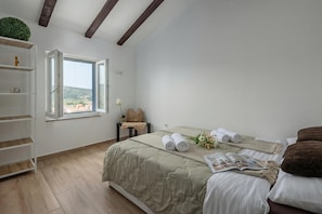 A bedroom with a bed, a window, a shelf, and a view of the outdoors.