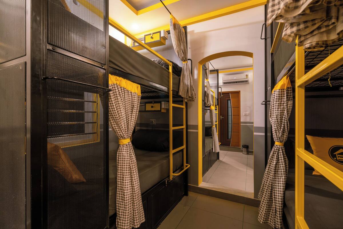A bunk bed room with checkered curtains, a ladder, and a mirror.