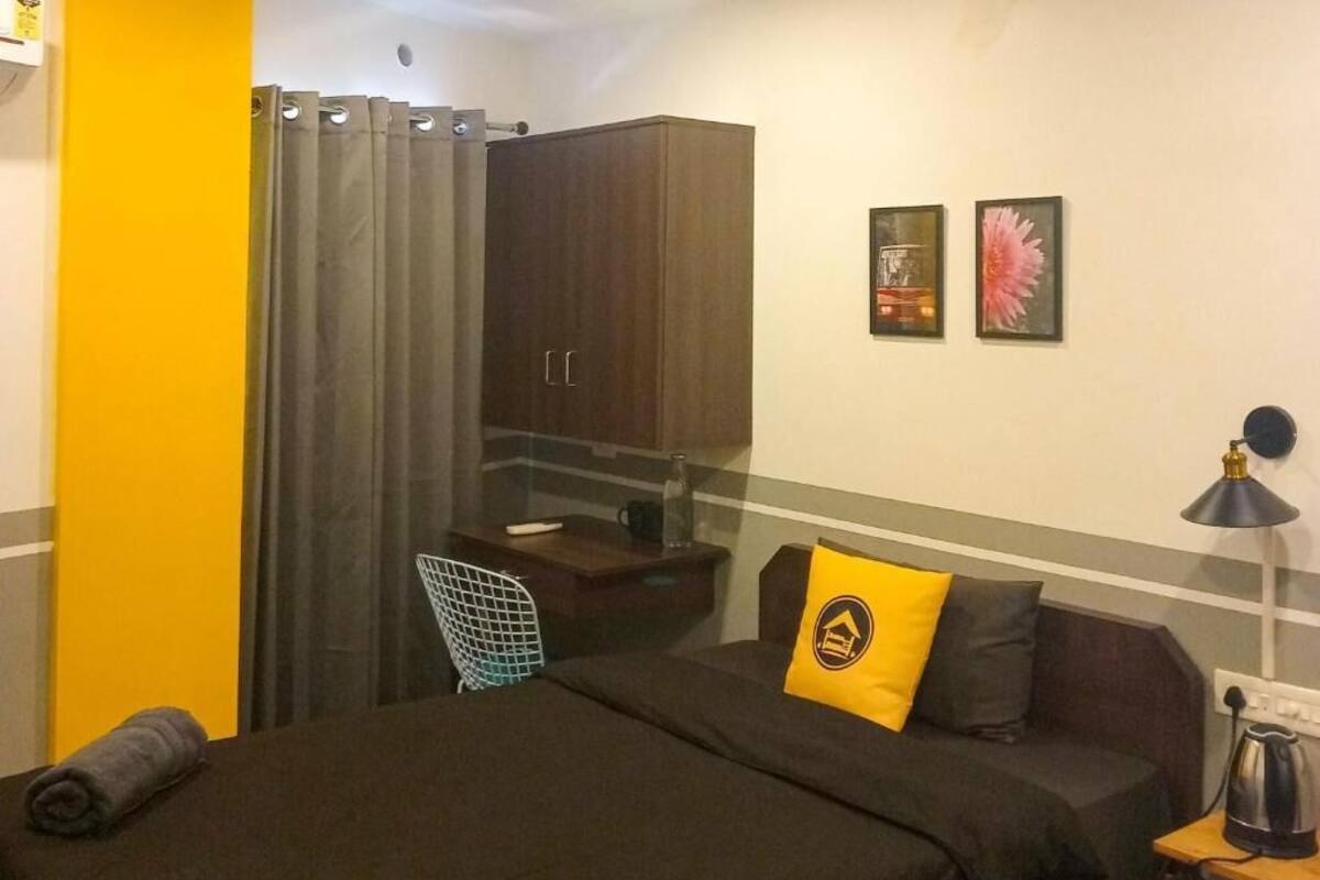 A bedroom with a bed, a desk, a chair, a lamp, and a wardrobe.