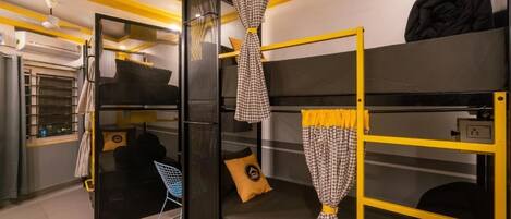Une chambre d’hôtel compacte avec des lits superposés, une petite kitchenette et un miroir avec des rideaux.