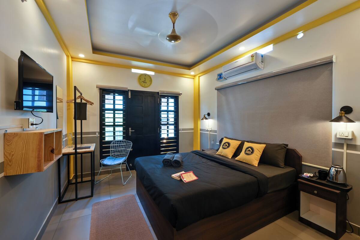 A neatly arranged hotel room with a bed, bedside table, lamp, and a desk with a chair.