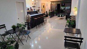 A modern cafe with a bar area, seating, and plants.