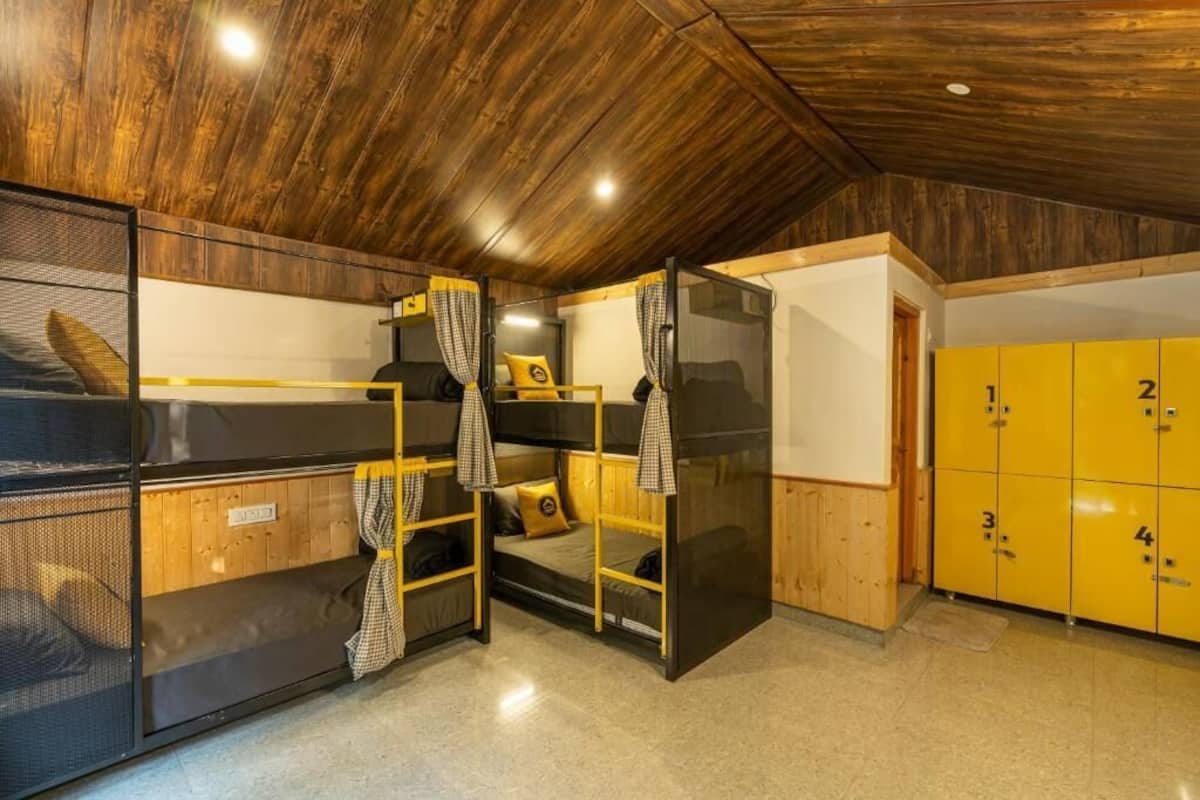 Une chambre de dortoir avec des lits superposés, un plafond en bois et des casiers jaunes.
