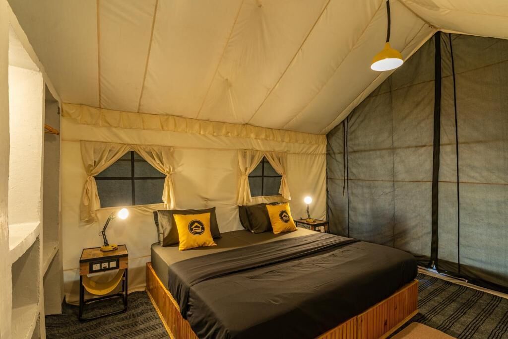 A bedroom with a bed, two bedside tables, a lamp, and curtains.