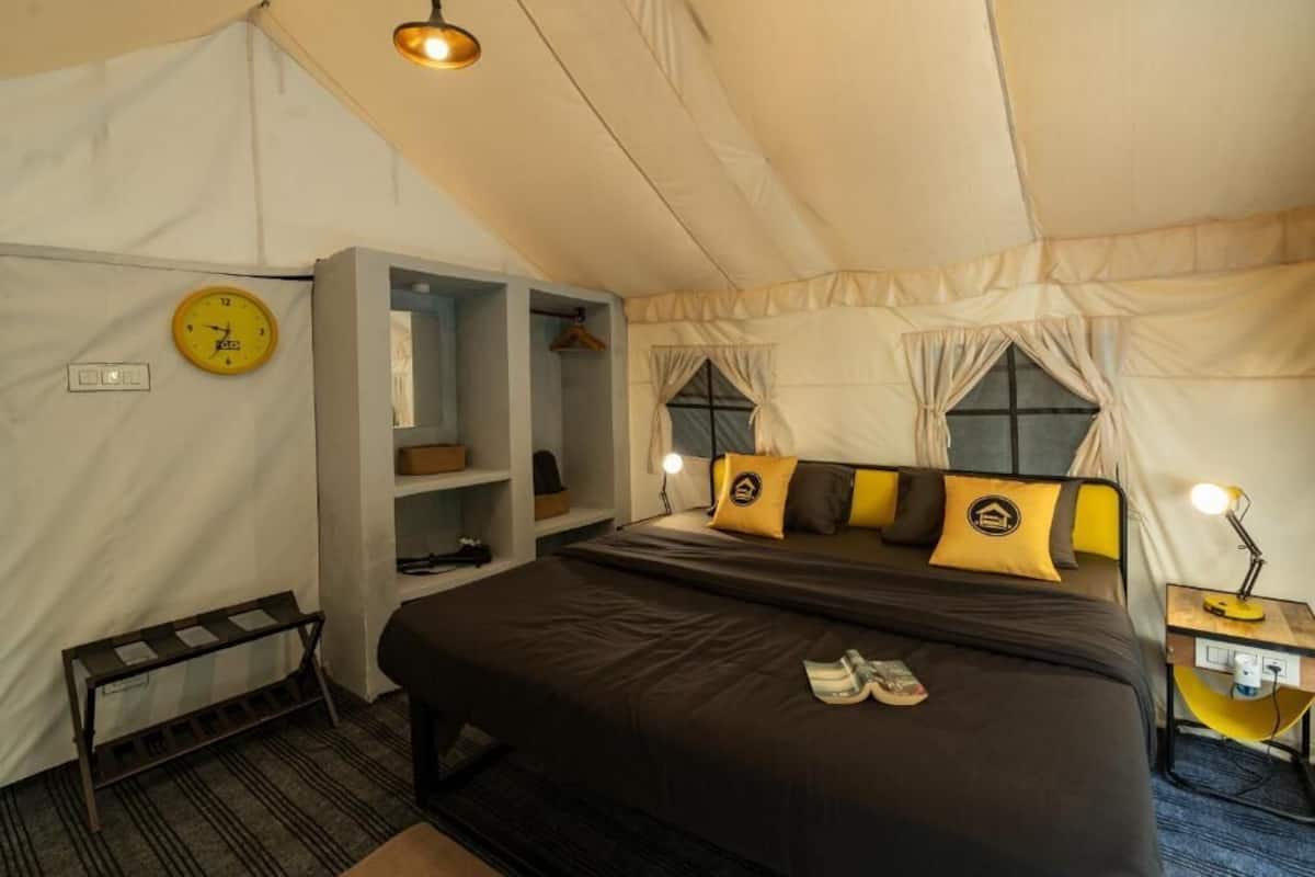 Une chambre à coucher avec un lit, une horloge, une étagère et un bureau avec une lampe.