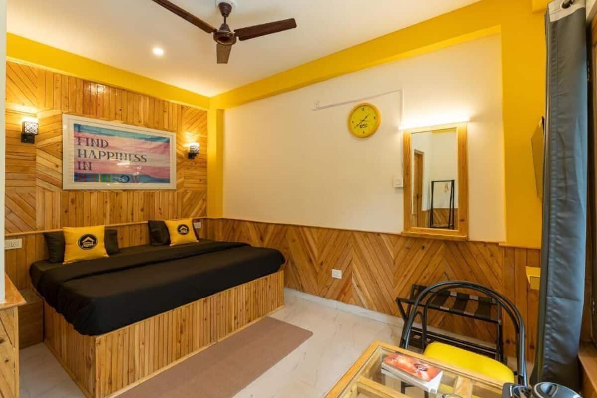 Une pièce comprenant un lit, une chaise, une table, un ventilateur de plafond, une horloge et une affiche motivante.