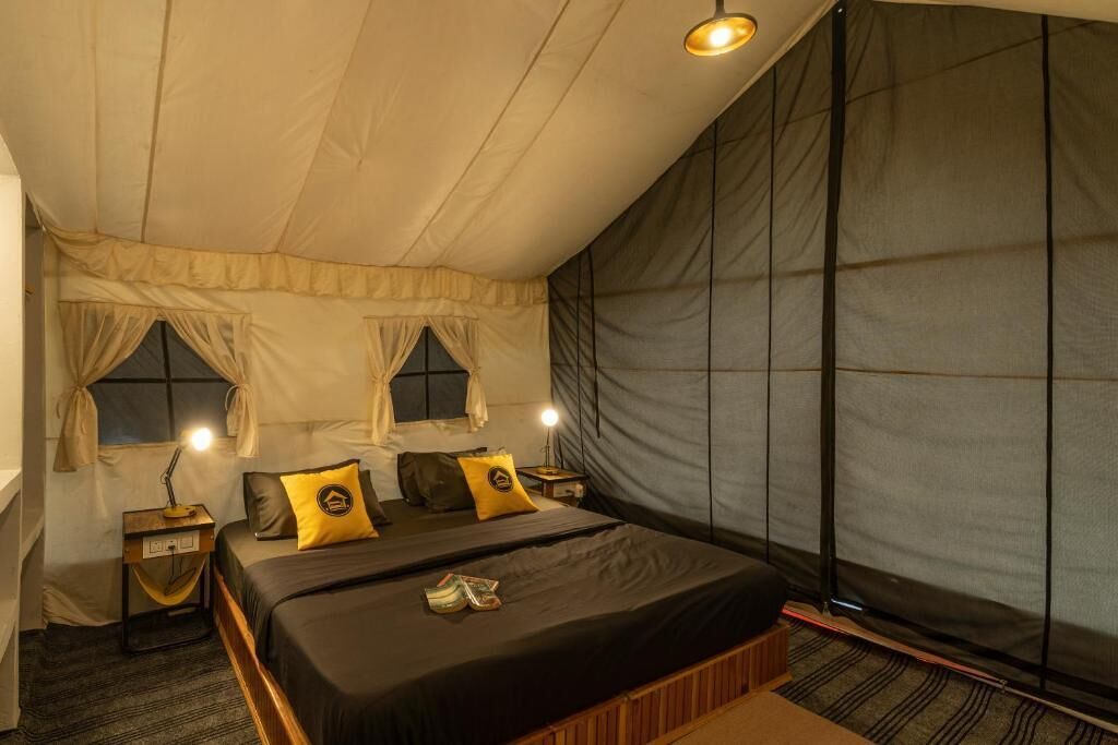 Un dormitorio con una cama grande, dos mesitas de noche con lámparas y una ventana con cortinas.