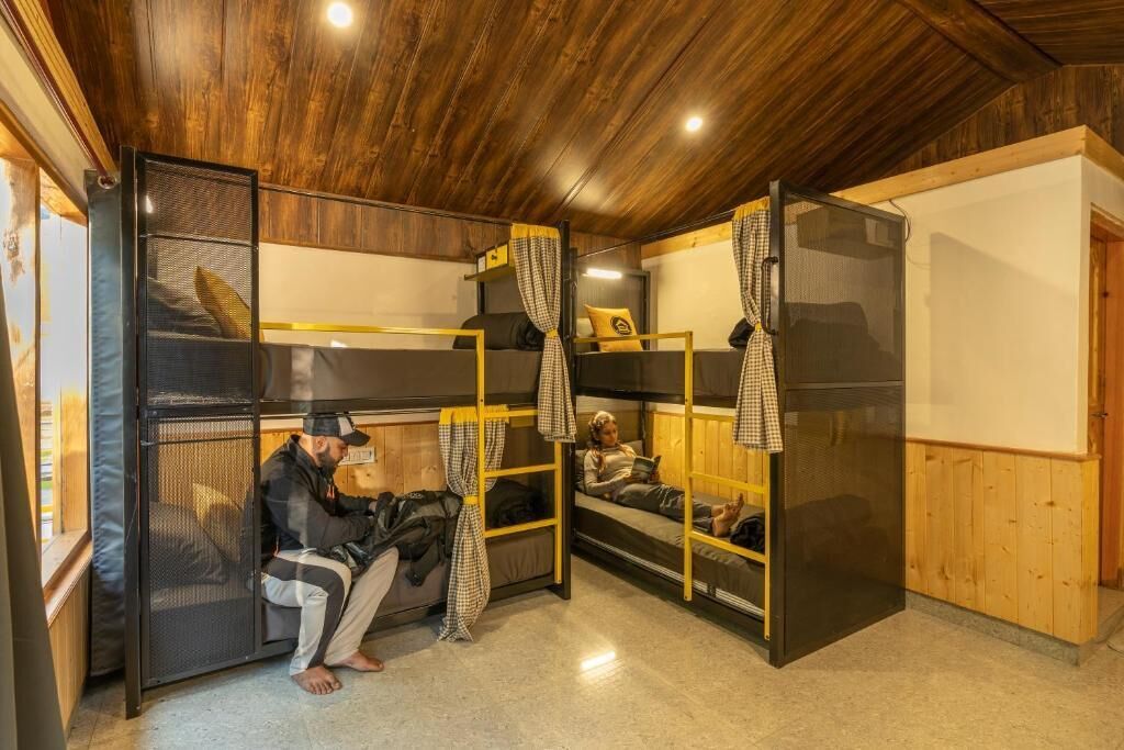 A bunk room with two beds, a window, and a wooden ceiling.