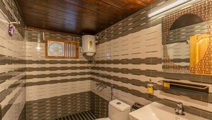 Ein Badezimmer mit gestreiftem Fliesenbelag, einer weißen Toilette, einem Waschbecken, einem Spiegel und einer Dusche.