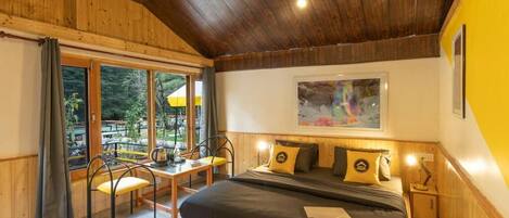 A bedroom with a large bed, wooden ceiling, and a view of the outdoors.