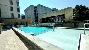 A rectangular swimming pool with a metal ladder, surrounded by a concrete deck.