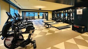 Een sportschool met trainingsapparatuur, een zwart-wit geruite vloer en een groot raam.