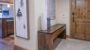Eine Holzbank mit einer Vase, einer Tür und einer Wand mit einem gerahmten Kunstwerk.