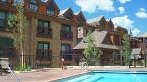 Ein Hotel mit Schwimmbad, Steinaußenwand und zahlreichen Fenstern.