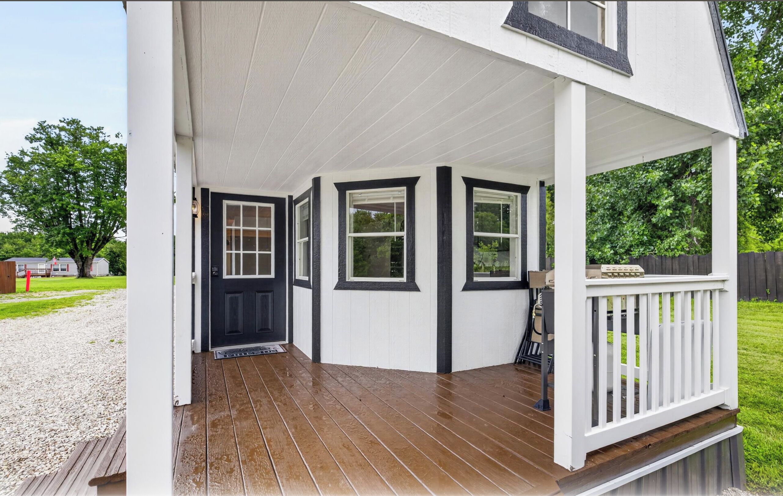 A house with a porch, a black door, and white walls.