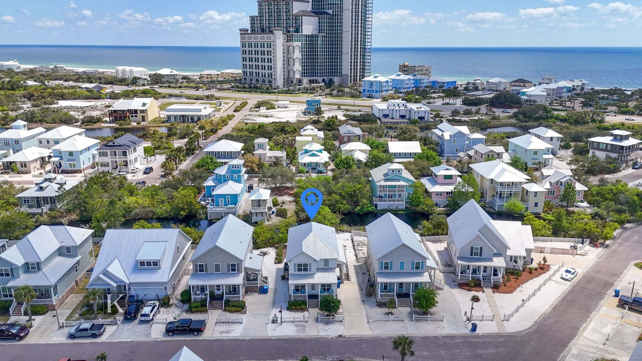 A coastal residential area with houses, a marina, and a large hotel building in the background.