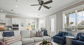 Ein modernes Wohnzimmer mit einer Couch, zwei Sesseln, einem Couchtisch und einem Deckenventilator.