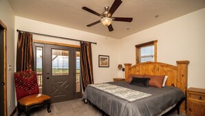 Une chambre à coucher comprenant un lit, une chaise, un ventilateur de plafond, une fenêtre et une porte donnant sur un balcon.