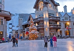 Un grand bâtiment doté de nombreux balcons et d’un toit enneigé, entouré d’un paysage hivernal.