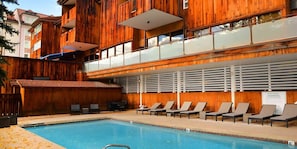 Relax by the large rectangular pool surrounded by lounge chairs and sunbeds.