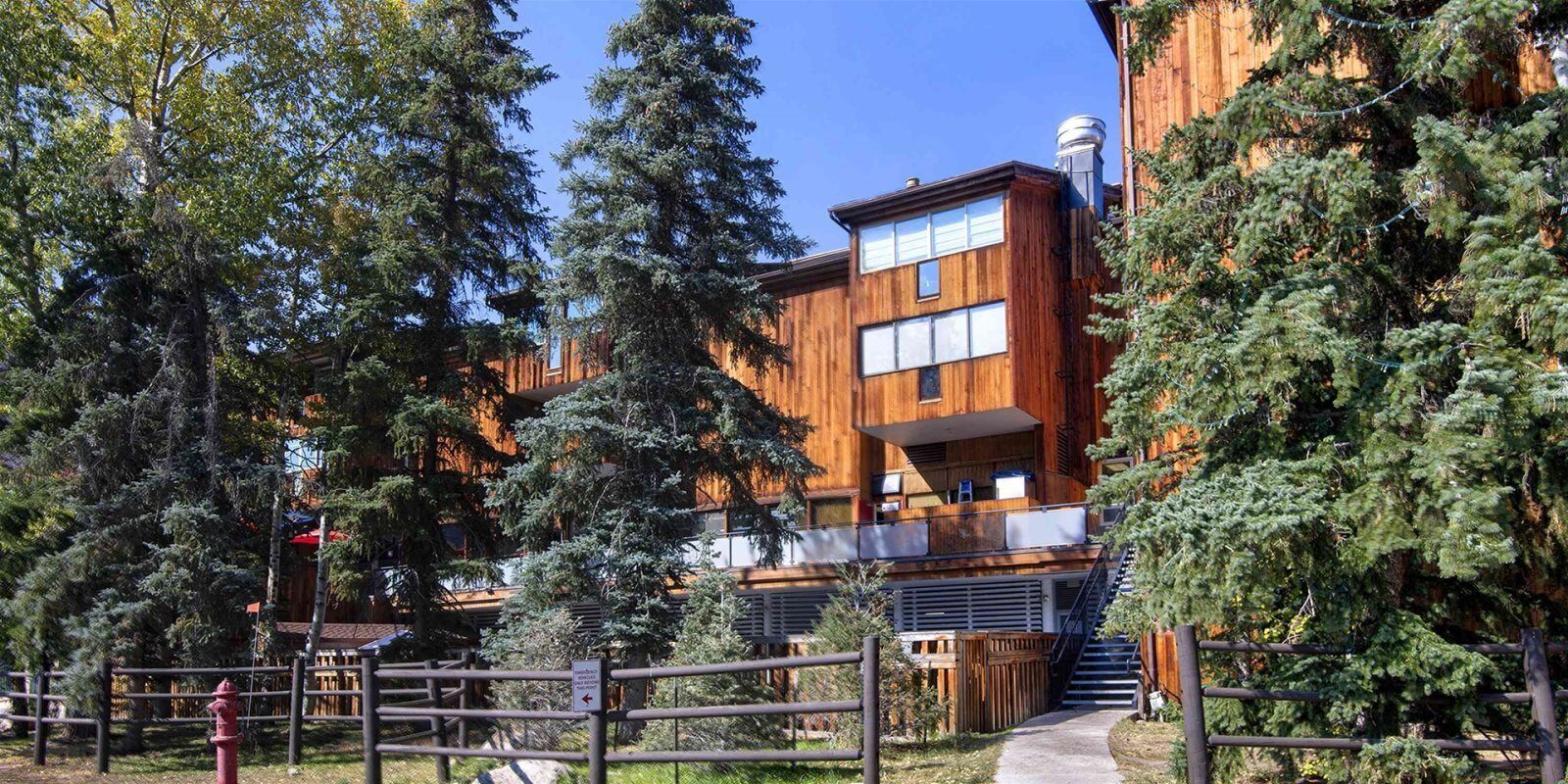 A modern wooden building with multiple windows and a staircase leading to a balcony.
