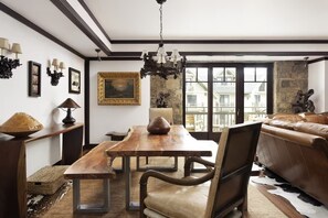 A dining area with a wooden table and chairs, a chandelier, and a view through large windows. - Luxury 3 Bedroom Residence at The Four Seasons in Vail Village (Vail)