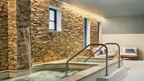 A spa area with a stone wall, a hot tub, and a seating area with a sofa and chairs. - Luxury 3 Bedroom Residence at The Four Seasons in Vail Village (Vail)