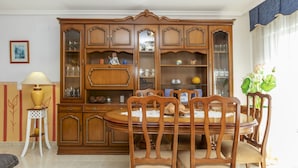 Un coin repas comprenant une table et des chaises en bois, entouré d’un grand meuble en bois doté de portes en verre.