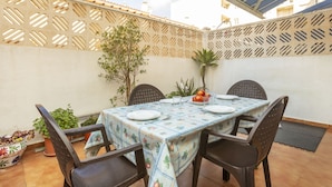 Une terrasse avec une table dressée pour deux personnes, entourée de chaises, sous une marquise bleue.