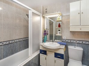 Een moderne badkamer met een bad, wastafel, toilet en spiegel.