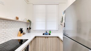 Una cocina moderna con azulejos blancos tipo metro, un refrigerador de acero inoxidable y armarios de madera.