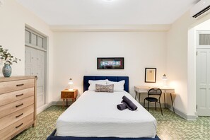 A neatly arranged bedroom with a bed, a desk, a chair, a dresser, and a door. - Bright Apartment in Miramar with Equipped Bathroom and Prime Location (San Juan)