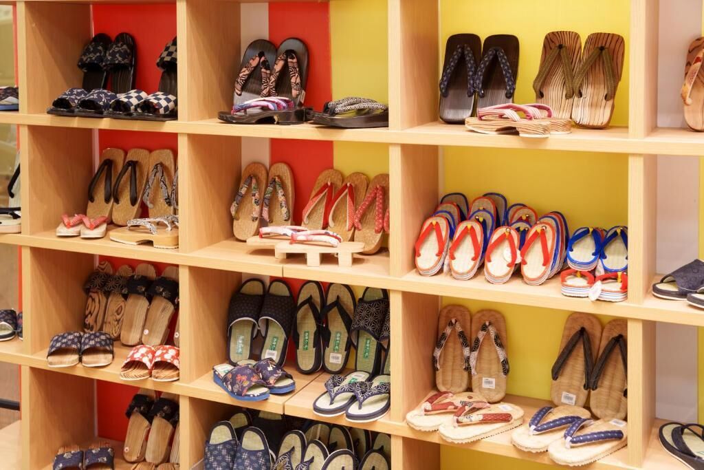 A shoe display with multiple shelves filled with various styles of sandals and flip-flops.