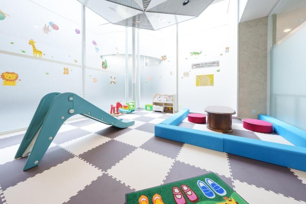 Zona de juegos infantiles con juguetes coloridos, un tobogán y asientos cómodos.