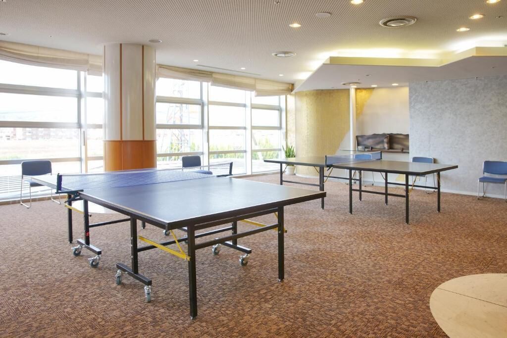 A conference room with two tables, chairs, and a large window providing natural light.