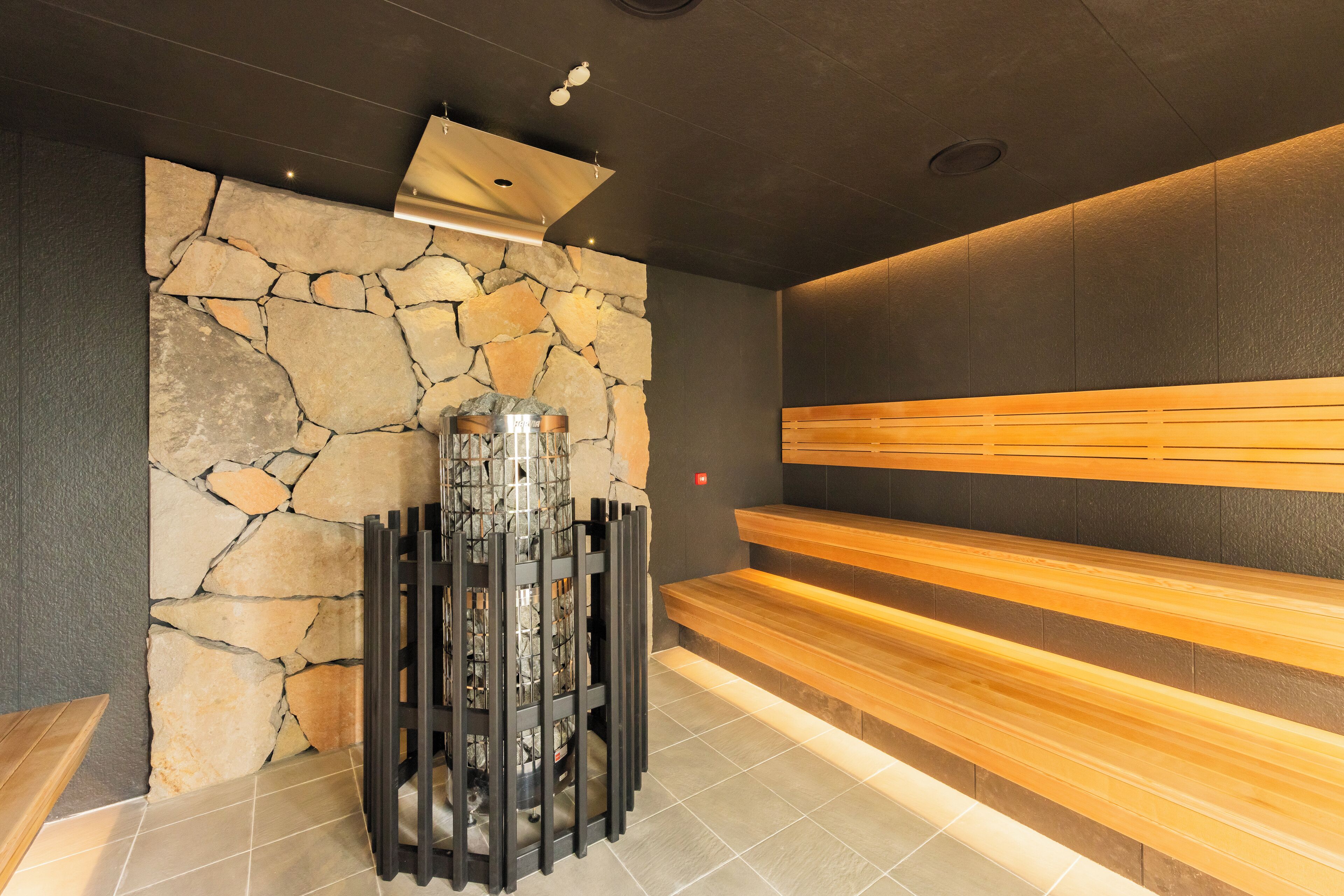 Un espace de bien-être avec des murs en pierre, des bancs en bois et une fontaine centrale.