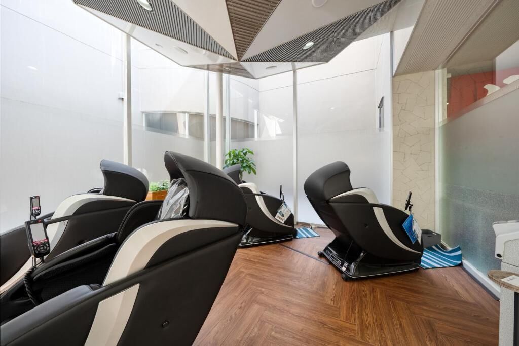A modern room with three massage chairs, a small table with a plant, and a large window.