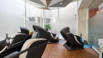 A modern room with three massage chairs, a small table with a plant, and a large window.