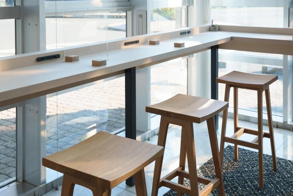 Un interior moderno con una encimera larga, dos taburetes de madera y un separador de vidrio.