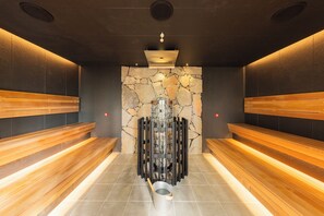 Een sauna met houten banken, een stenen muur en een centrale verwarming.