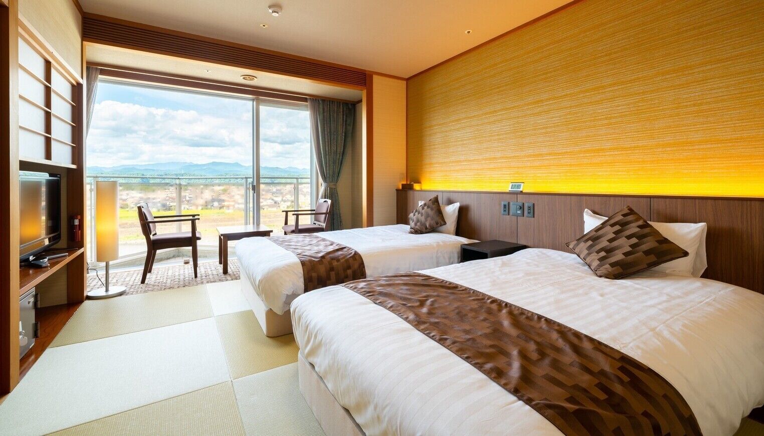 Ein Hotelzimmer mit zwei Betten, einem Fernseher, einem Schreibtisch und Blick ins Freie.