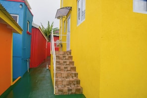 Steps lead up to a charming building with a white window and black awning.