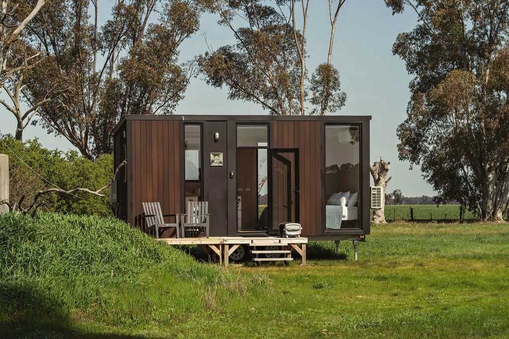 Eine kleine, moderne Hütte mit einer Terrasse, zwei Stühlen und einem Tisch.