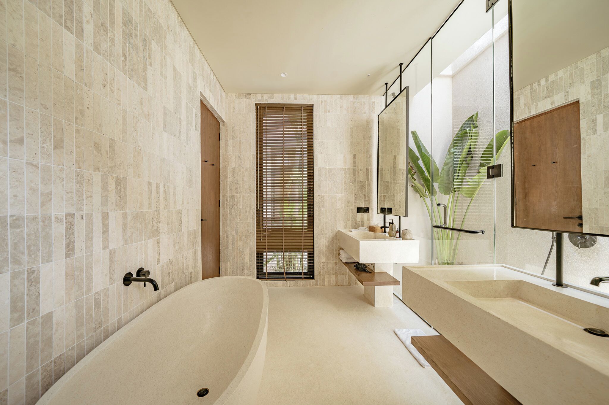A modern bathroom with a freestanding bathtub, a large mirror, and a wooden vanity.